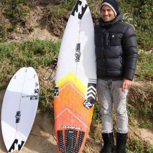 Josh Enslin stands next to his surfboard.