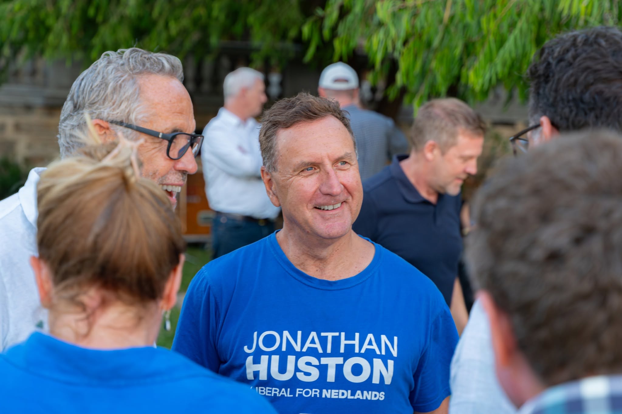 A man wearing a Liberal shirt speaking with other men