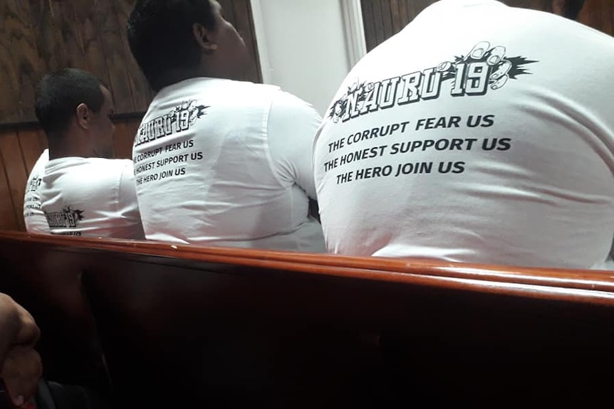 Members of the Nauru 19 sit in court wearing T-shirts that say 'the corrupt fear us, the honest support us, the hero join us'.