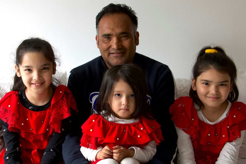 A man sits with three young girls all dressed in red.