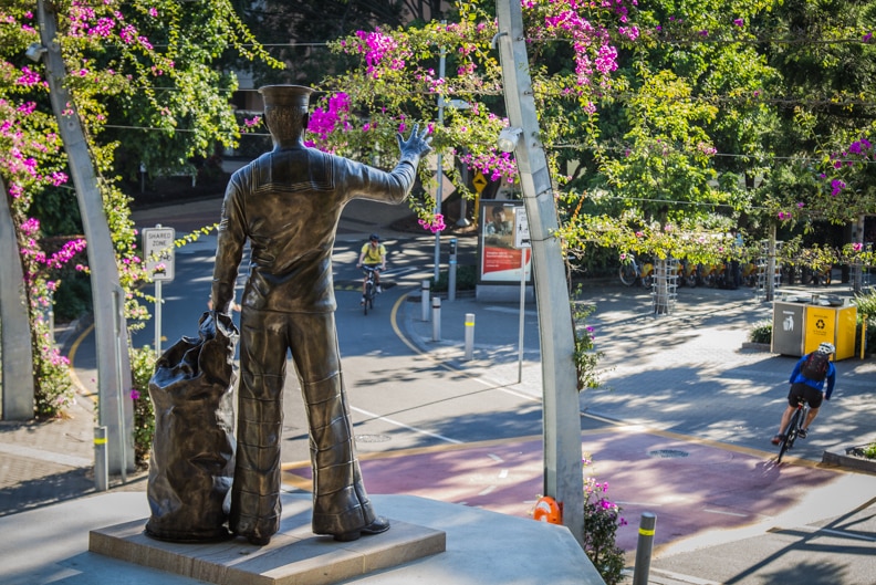 The soldier statue waves in the direction of the river with his ship bag at his side.