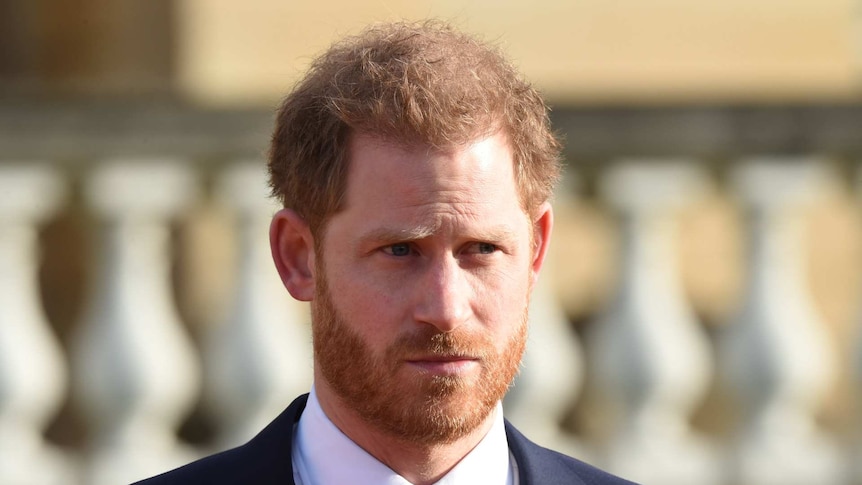 Prince Harry with a beard and furrowed brow wearing a suit and tie