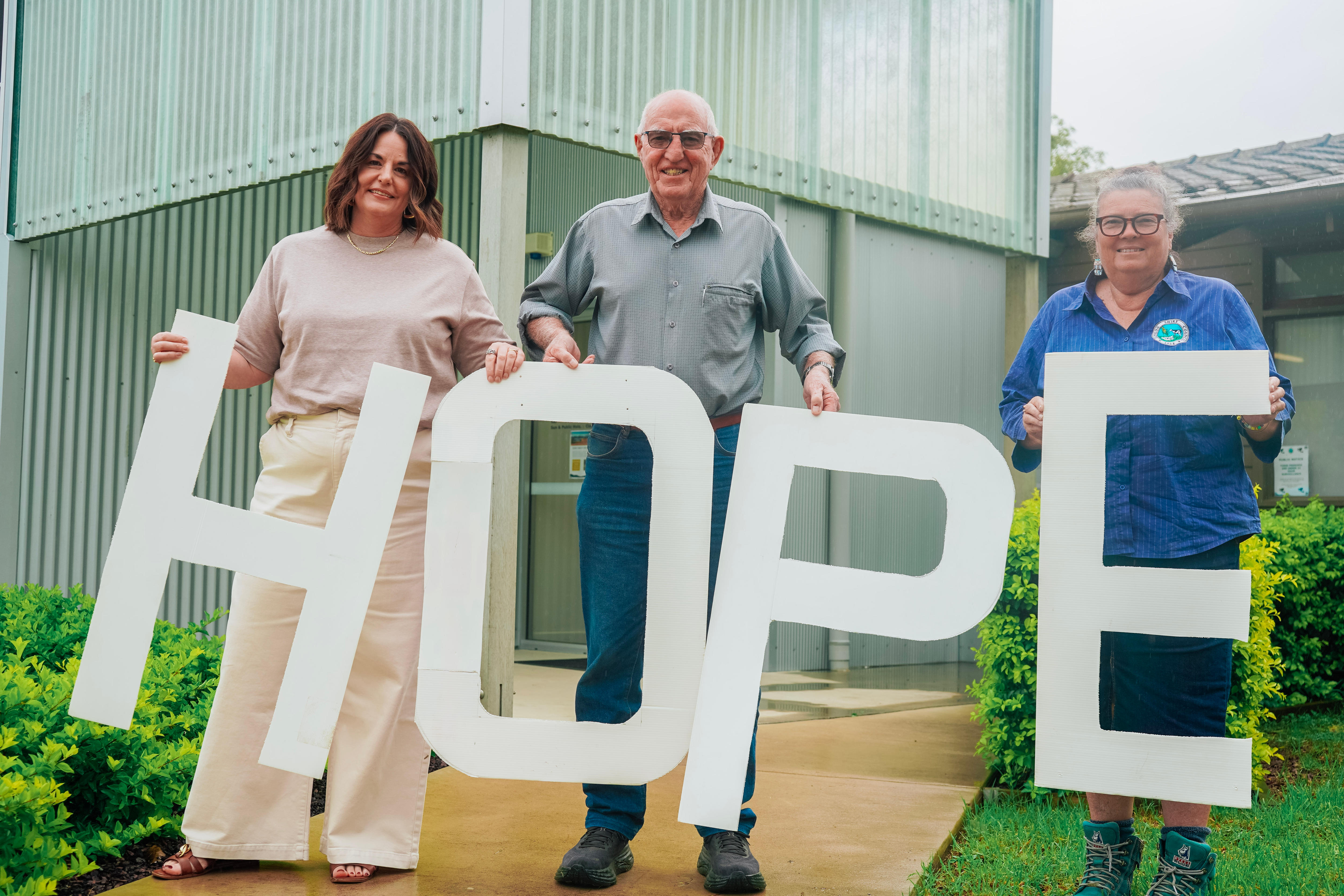 three people standing together, holding large letters that spell 'hope'