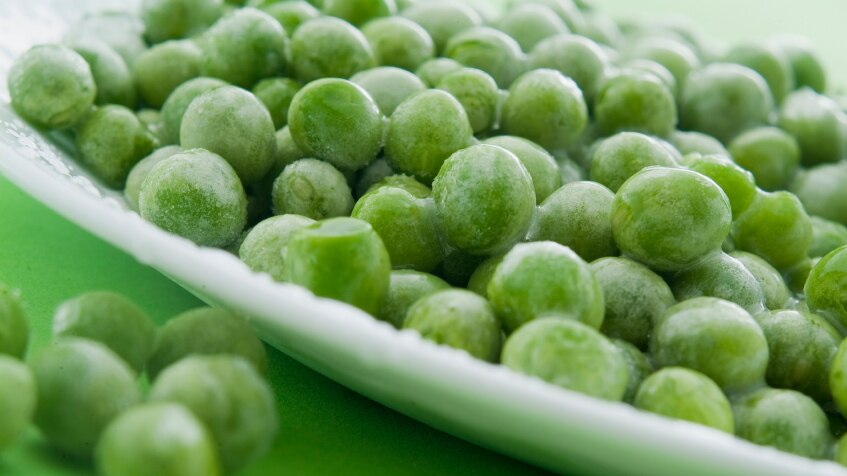 A plate full of frozen peas