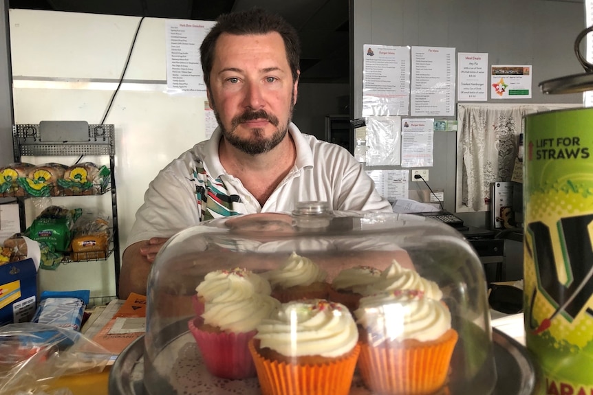 Man standing behind cupcakes on a benchtop
