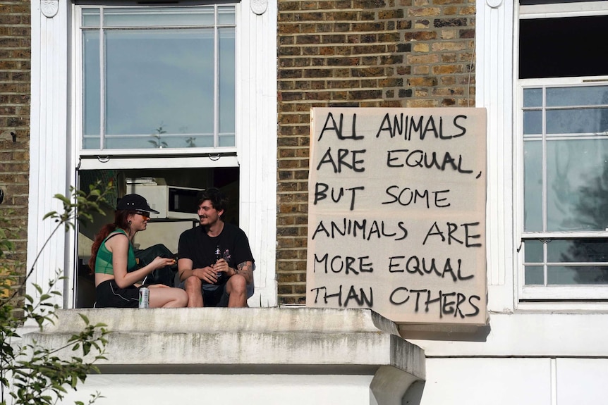 A cardboard sign in a window displays a famous excerpt from Orwell's Animal Farm.