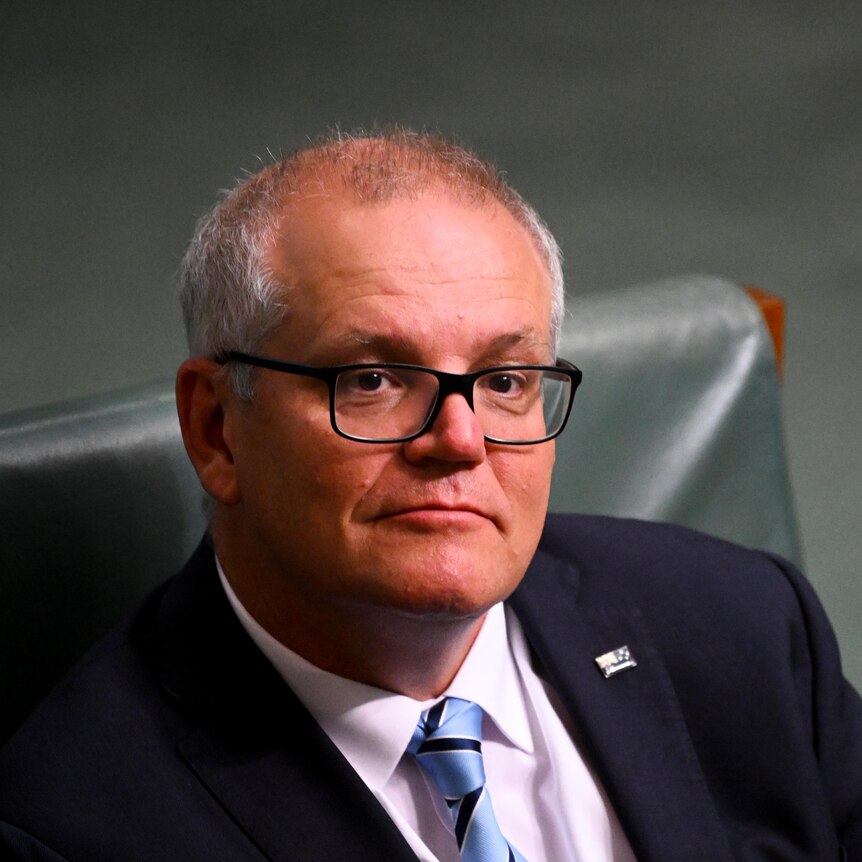 a man with glasses sitting down in parliament house