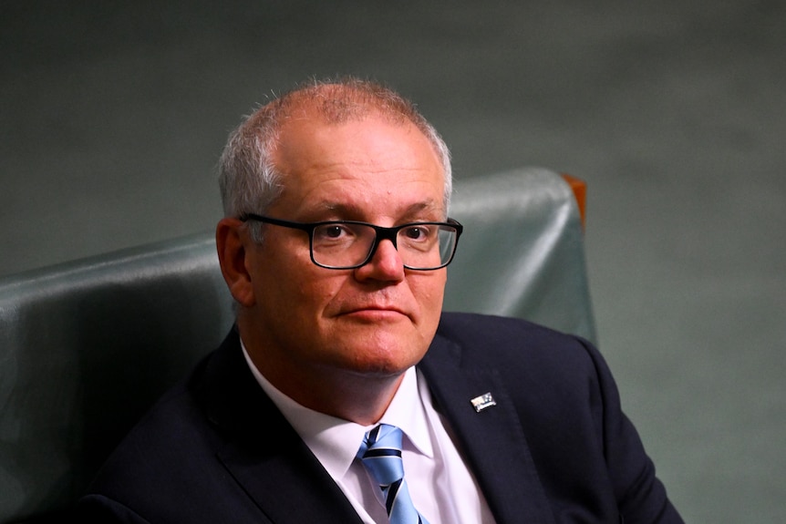 a man with glasses sitting down in parliament house