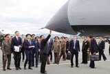 Kim Jong Un stands at the front of a missile and reaches up and touches it with his hand.