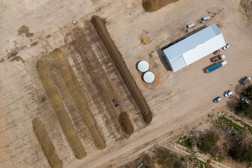 An aerial view of a shed, water tanks and rows of compost.