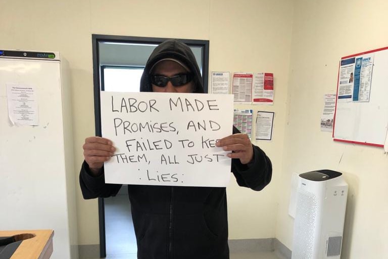 A detainee holds a sign accussing Labor of lying