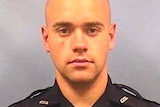 a headshot of a male police officer in uniform with a shaved head