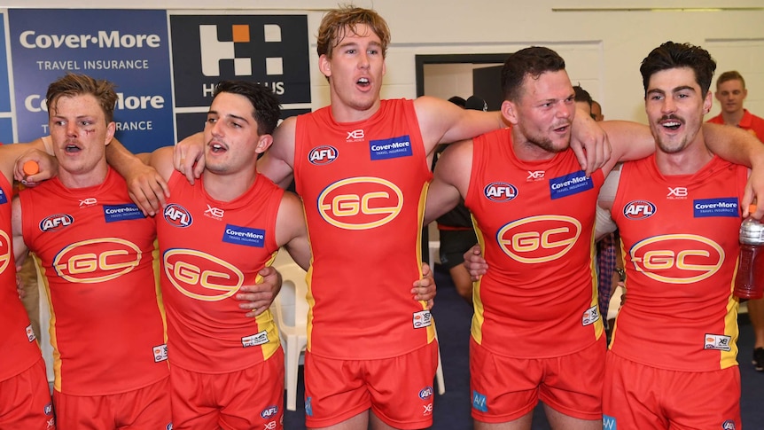 Gold Coast Suns including Tom Lynch (3L) and Steven May (4L) sing the song after beating Carlton.