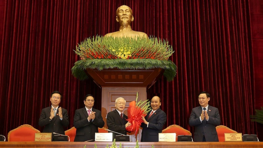 Vietnam's President and General Secretary of the Communist Party Nguyen Phu Trong (3rd L) receives flowers after win.