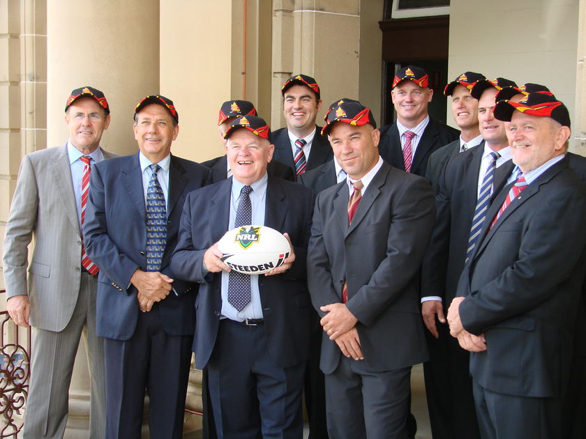 A group of men in suit jackets holding a football