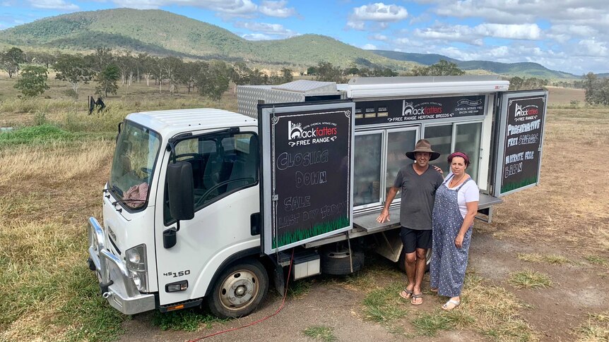 The owners of Backfatters Free Range Pig Farm stand in front of their cold truck of pork products at their property.