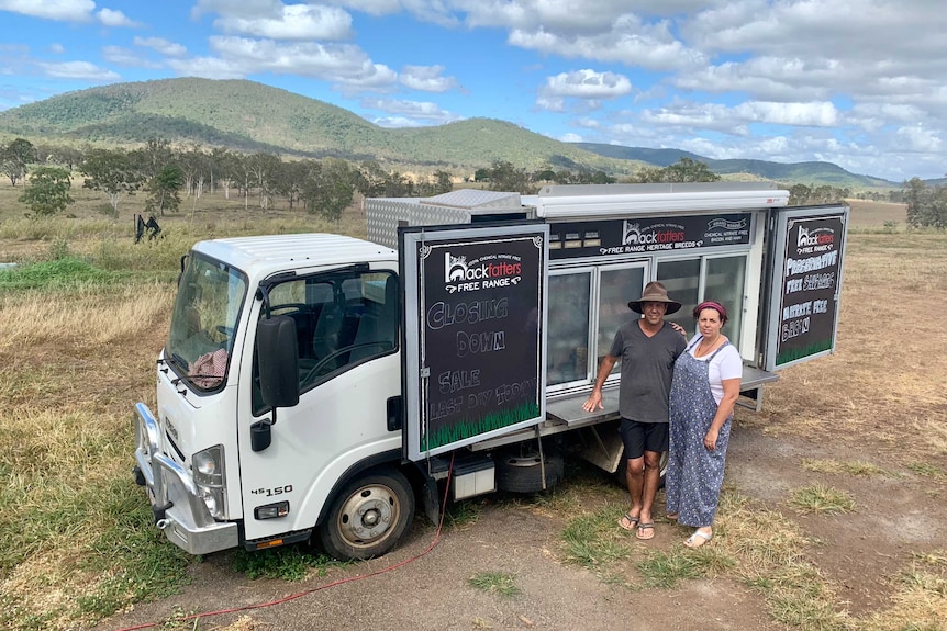 The owners of Backfatters Free Range Pig Farm stand in front of their cold truck of pork products at their property.