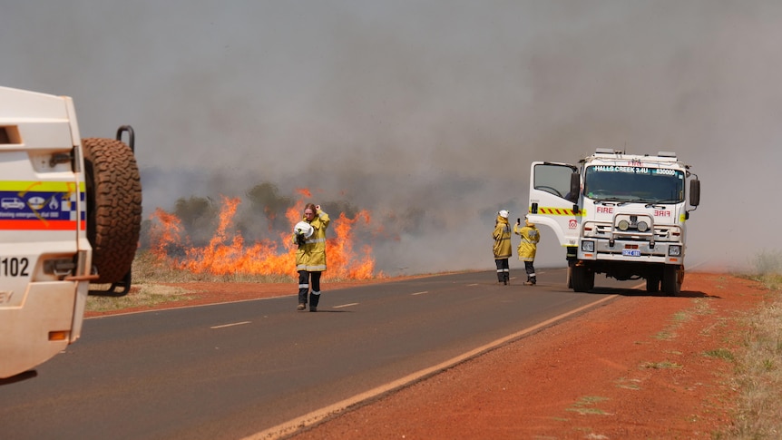 Firefighters respond to a bushfire with police in the foreground.