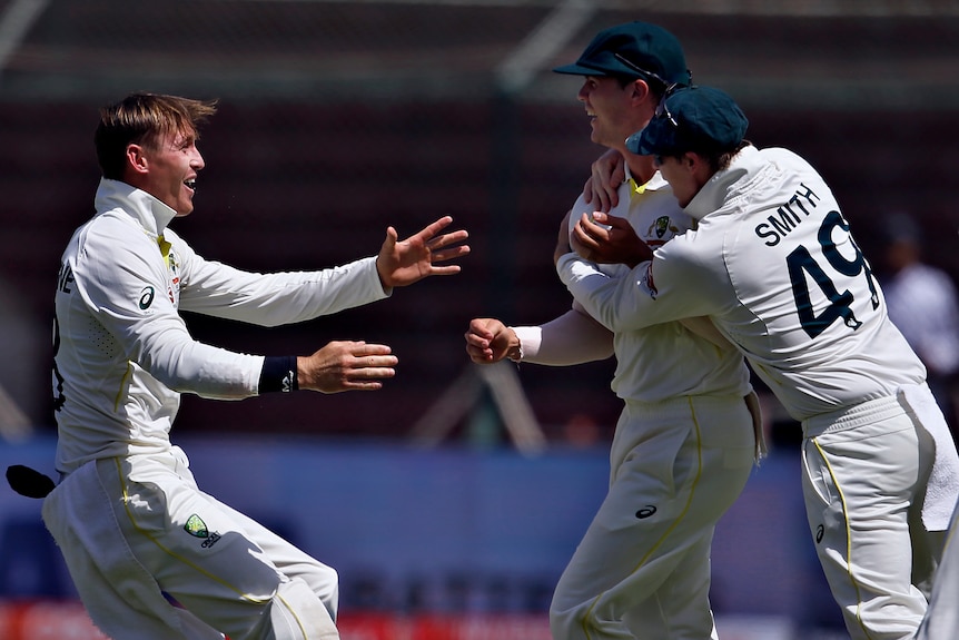 Australia crickters Marnus Labuschagne (left) and Steve Smith (right) run to hug Mitchell Swepson (centre) after a run-out.