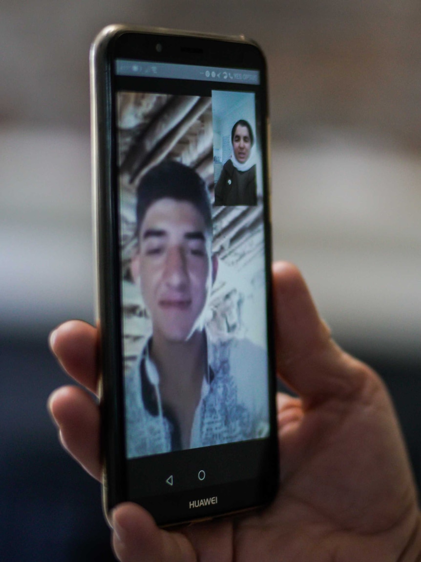 A telephone screen captures a FaceTime call between a young man and his mother.