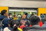 Commuters pile on into a train carriage with open doors