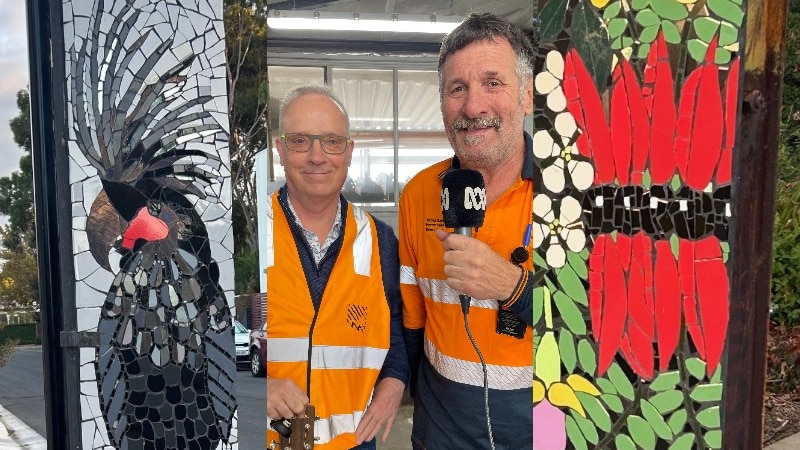 two men in hi-vis vests between two colourful posts with mosaic artwork
