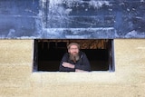 a man leans inside a new window framed by a hempcrete wall
