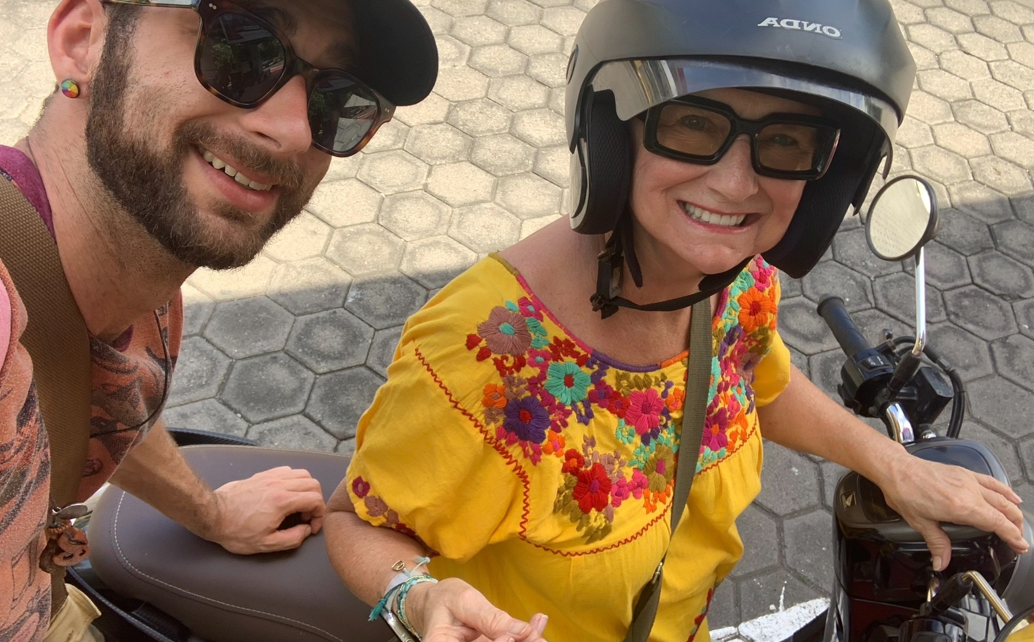 A middle aged woman leaning on a motorbike, smiling