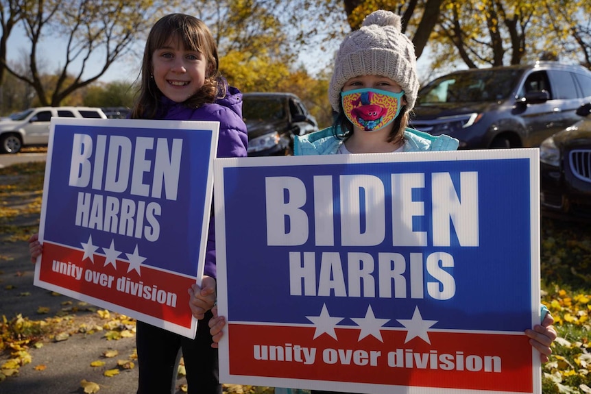 Two children, one wearing a mask, hold signs supporting the Biden-Harris bid in the US presidential election.