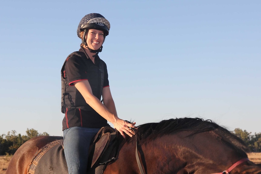 A jockey on top of a horse smiles
