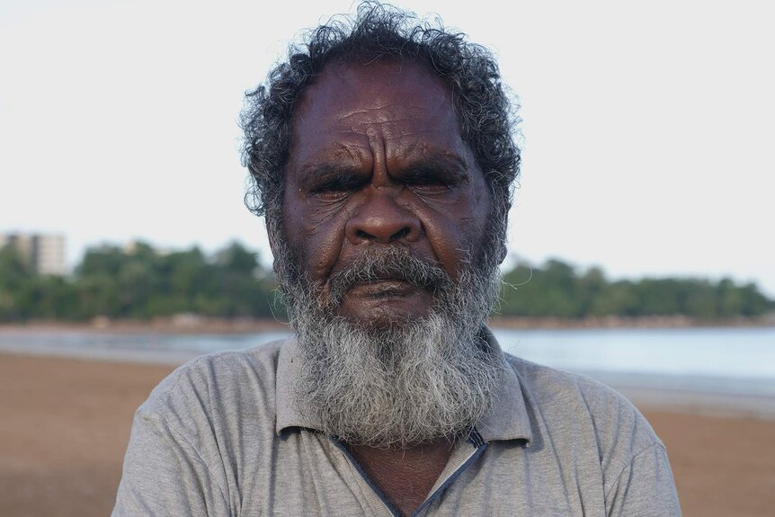 A photo of an Indigenous man standing on a beach.
