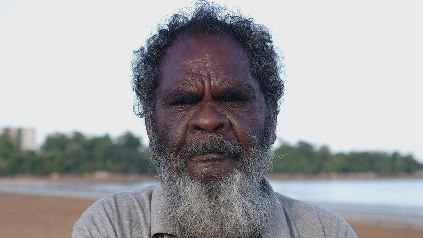 A photo of an Indigenous man standing on a beach.