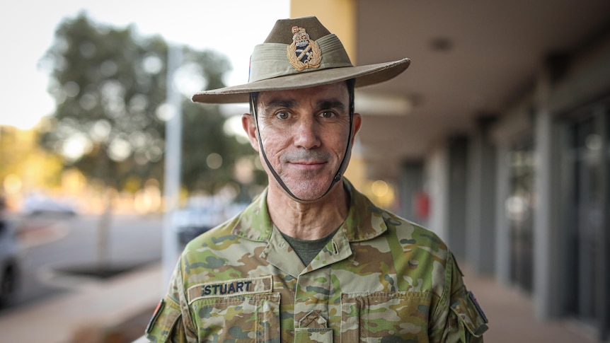 A man in army uniform standing on a street.