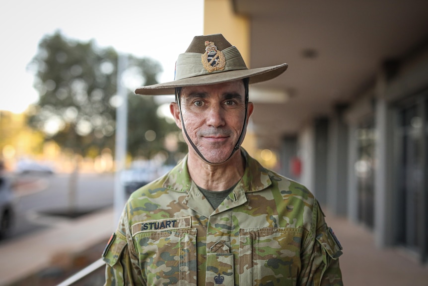 A man in army uniform standing on a street.