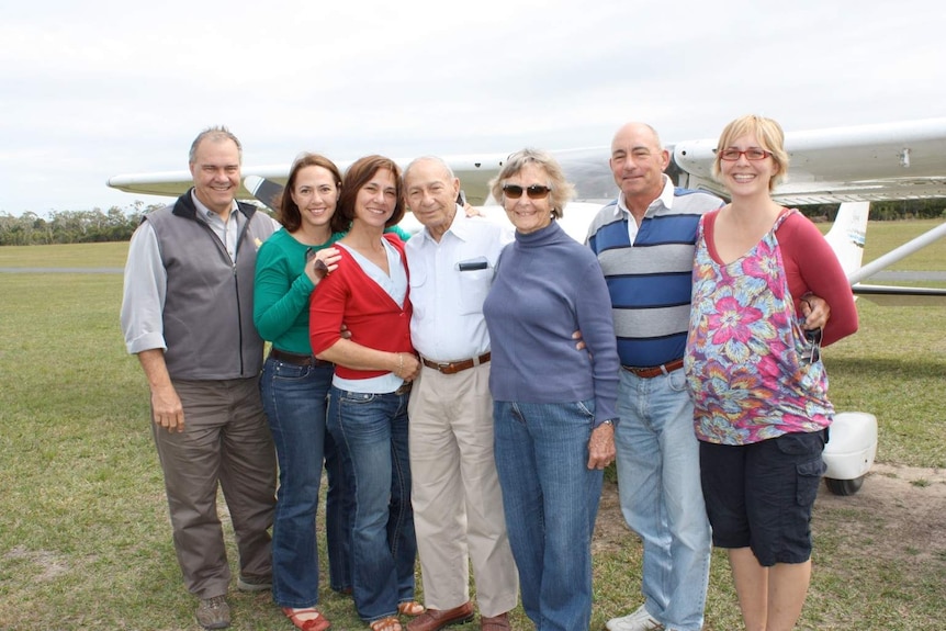 The Millar family in a field with a light plane behind