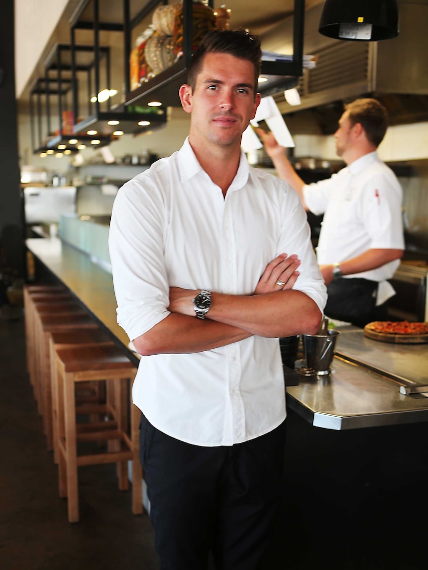 A man in a white shirt stands in a kitchen