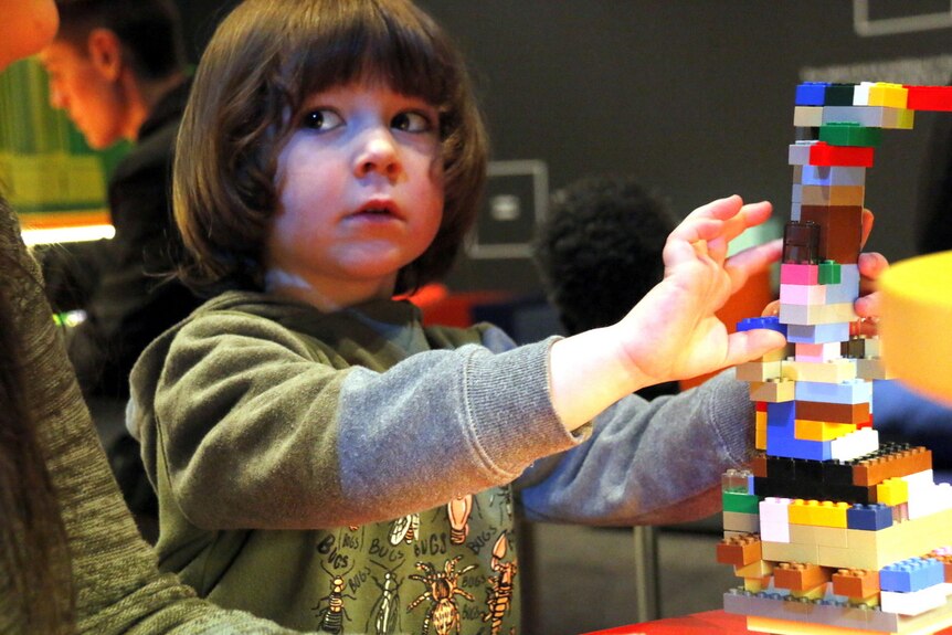 Young boy builds Lego tower