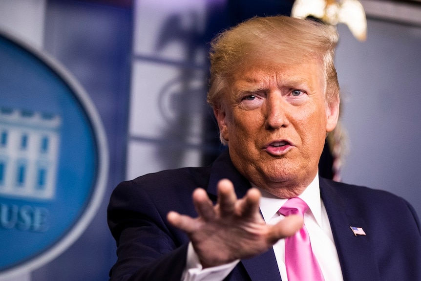 Donald Trump dressed in a suit gesturing during a speech.