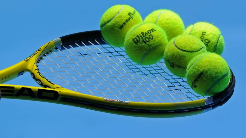 A tennis racquet with several tennis balls balancing on its strings