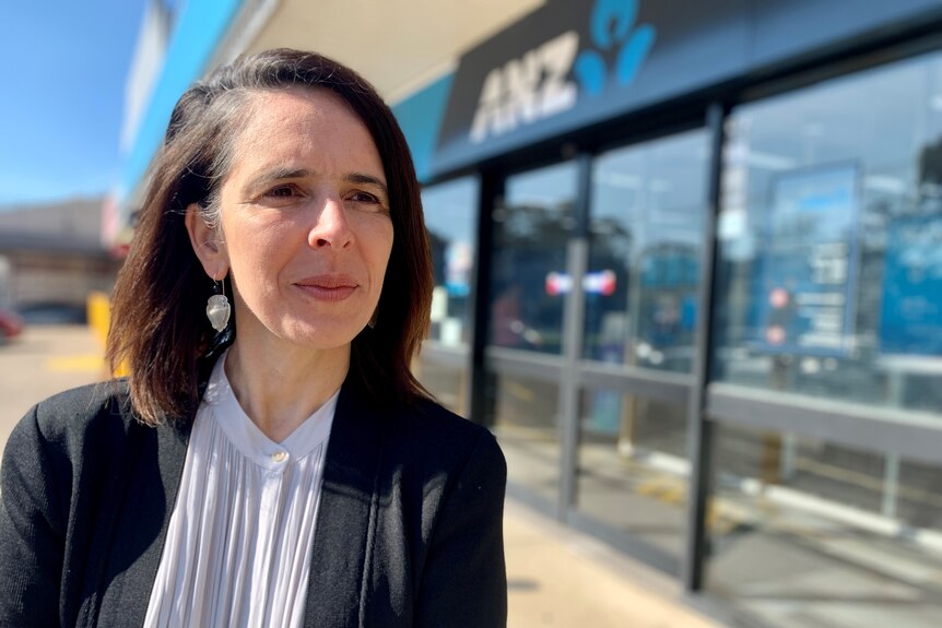 A woman stands outside an ANZ bank branch.