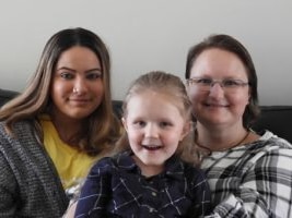 A woman, Rowena, sitting with her two daughters.