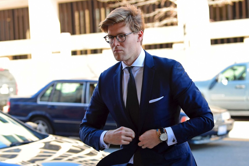 Alex van der Zwaan does up a button on his suit as he walks towards a court.