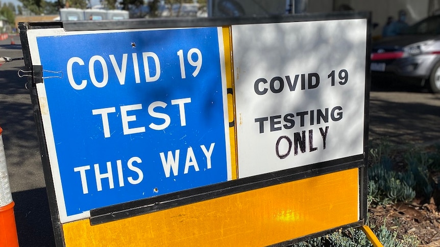 A COVID-19 testing sign sits outside a drive-through site.