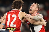 Max King and Tim Membrey hug while a Carlton player leans over in disappointment