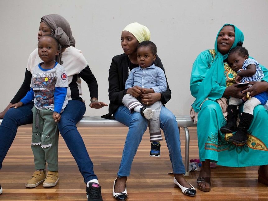 Three mums and their children sit on the sidelines