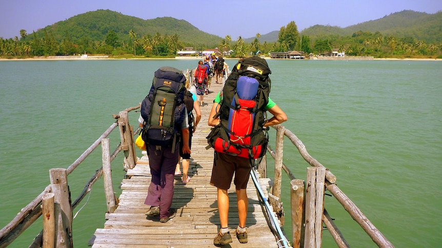 Backpackers walking over a bridge.