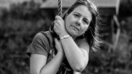 Black and white photo of a woman sitting on a rope swing