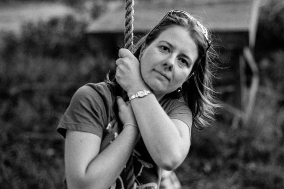 Black and white photo of a woman sitting on a rope swing