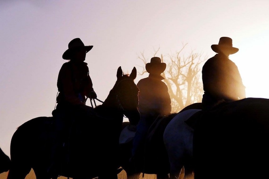 The sun sets on three drovers.