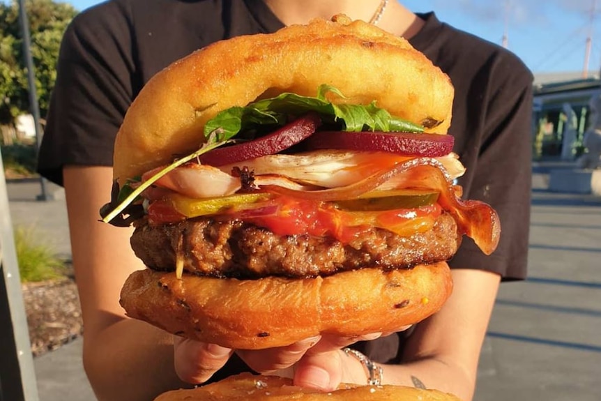 A woman holds a hamburger